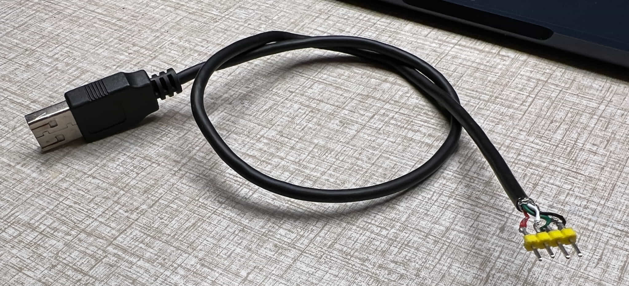 A USB cable with the bare wire ends exposed and soldered to a 4-pin 2.54mm header in an expert (not expert) manner.