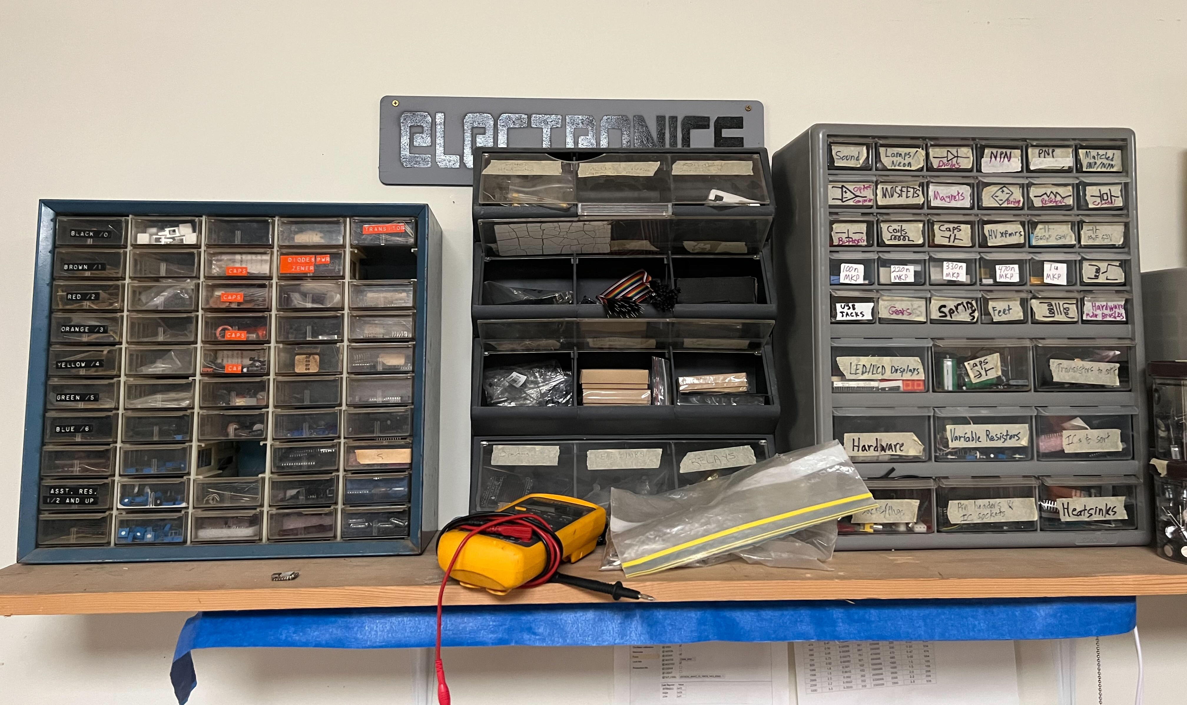 A shelf with three sets of Akro-Mills style component drawers. The drawers look old.